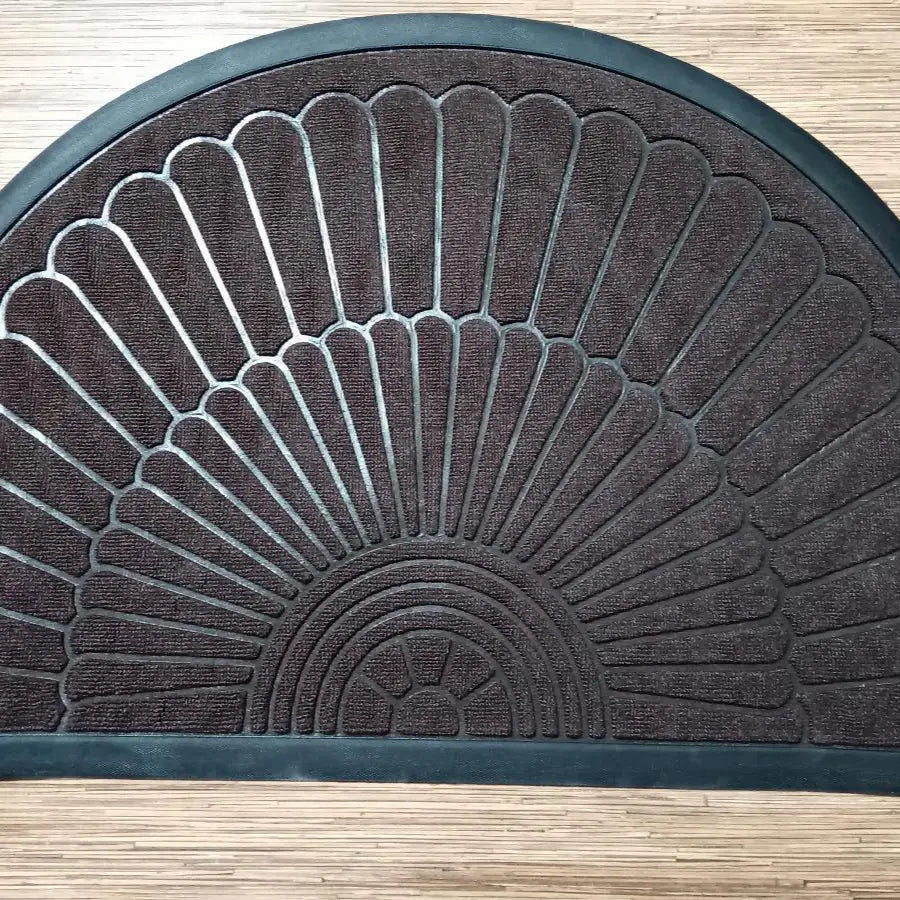 Paillasson semi-circulaire marron foncé avec un motif texturé en forme d’éventail et un bord caoutchouté.