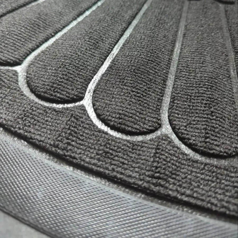 Tapis en caoutchouc texturé gris foncé avec des crêtes surélevées et incurvées et des bords cousus.