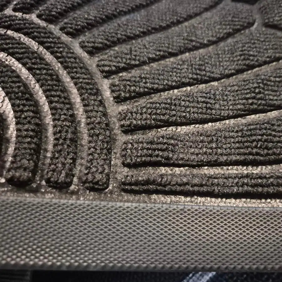 Semelle de chaussure en caoutchouc noir avec un motif de crampon texturé et une paroi latérale en maille.