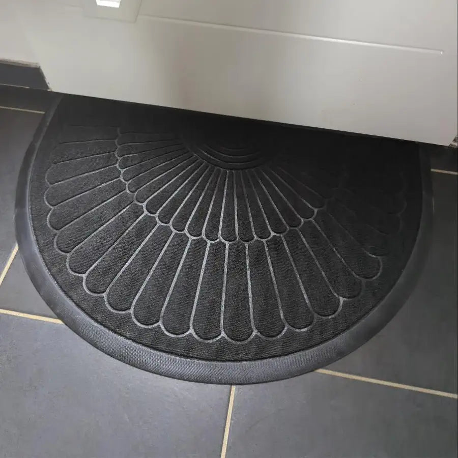 Tapis semi-circulaire noir avec un motif texturé en forme d’éventail.
