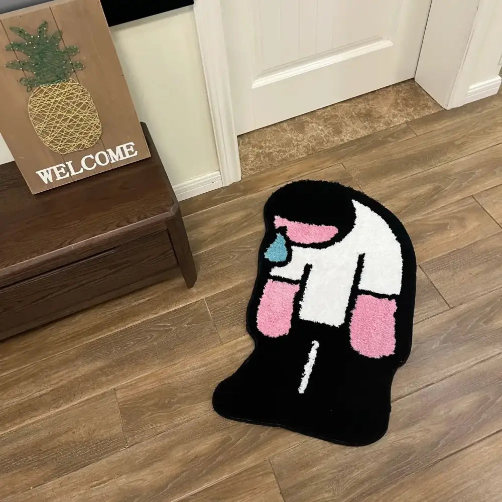 Tapis en peluche noir, blanc et rose en forme de personnage de dessin animé avec une larme.