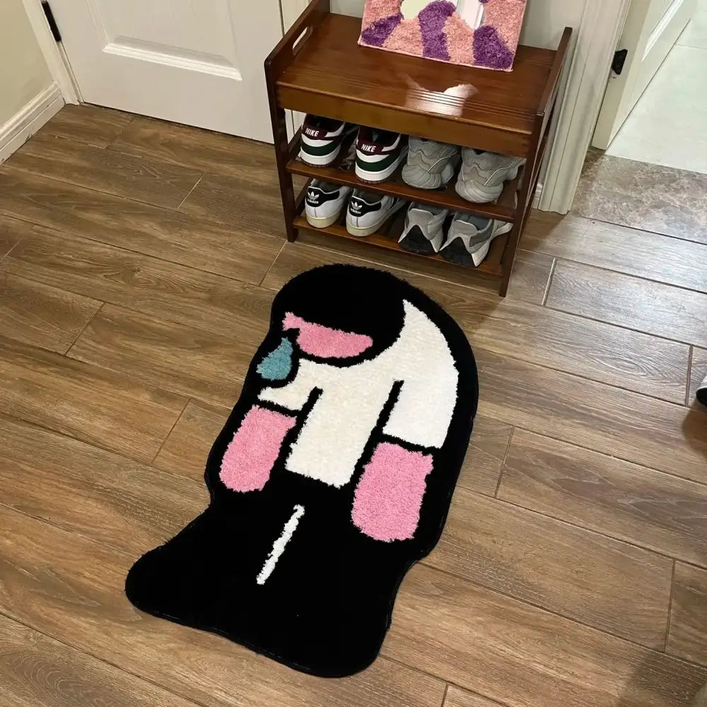 Tapis noir en peluche en forme de personnage de dessin animé avec des accents rose et blanc.