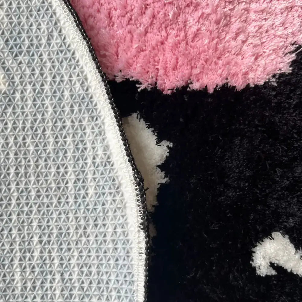 Tapis en peluche rose et noir avec une surface texturée et hirsute.