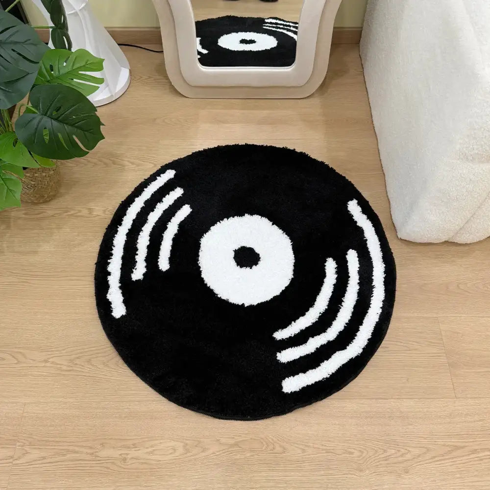 Tapis en vinyle noir en forme de disque vinyle avec cercles concentriques blancs et lignes, matériau moelleux.