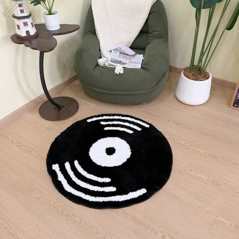 Tapis en forme de disque vinyle noir avec rainures blanches et design en spirale, matériau moelleux.