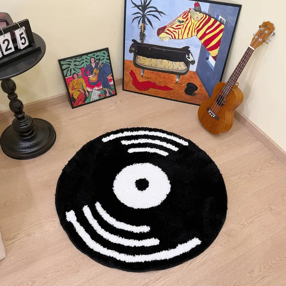 Tapis en forme de disque vinyle noir avec cercles concentriques blancs et rainures, matériau moelleux.