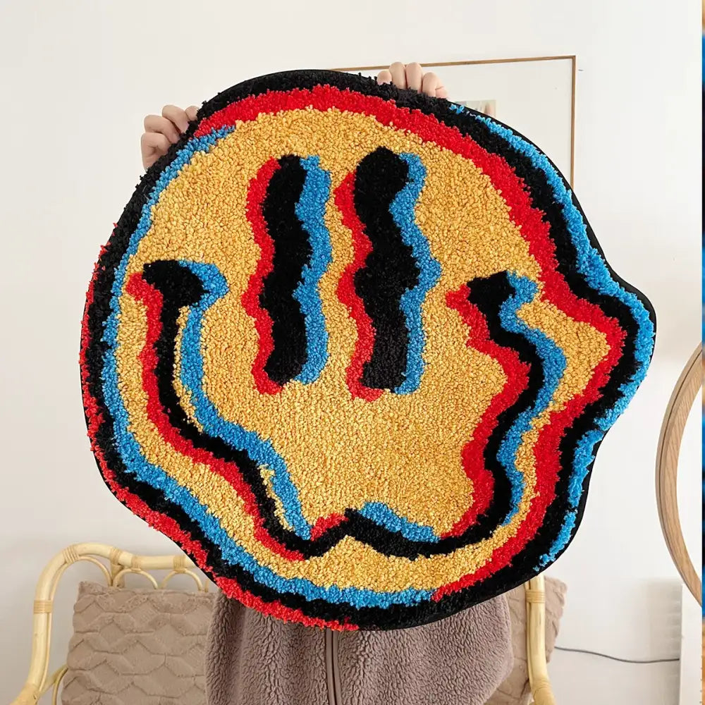 Tapis effet 3d rond en peluche avec visage souriant coloré jaune rouge bleu et noir créant une illusion doptique