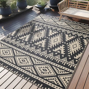Tapis d’extérieur à motif géométrique noir et blanc avec texture tissée.