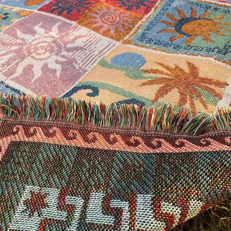 Une couverture tissée en patchwork coloré ornée de motifs de soleil et de palmiers dans des tons vifs, avec un bord frangé.