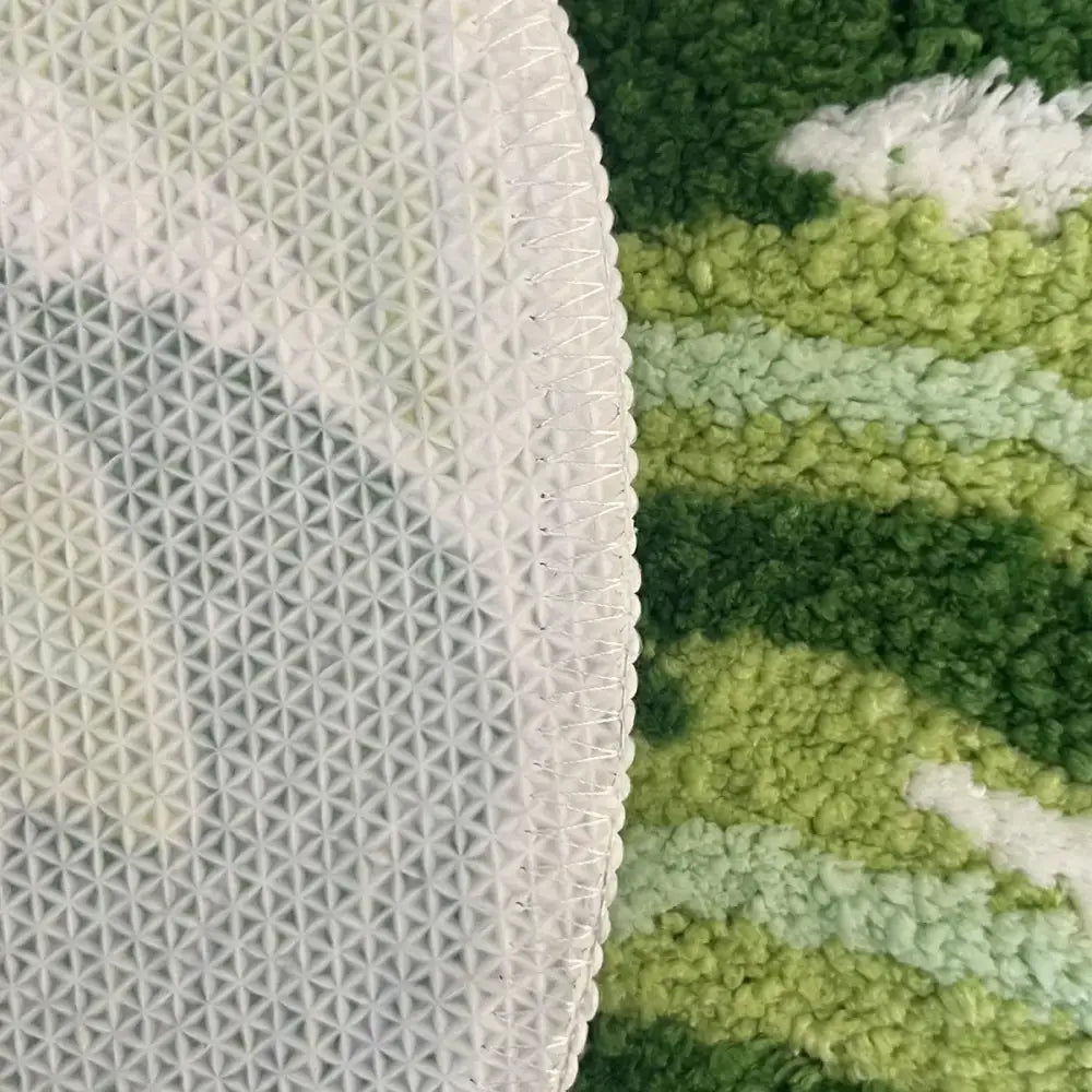 Tapis de bain vert rayé avec dos texturé blanc et motif géométrique.