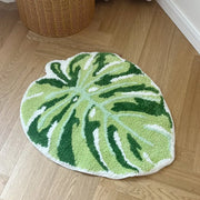 Tapis de bain en forme de feuille verte avec des accents blancs et vert foncé, fabriqué en matériau moelleux.