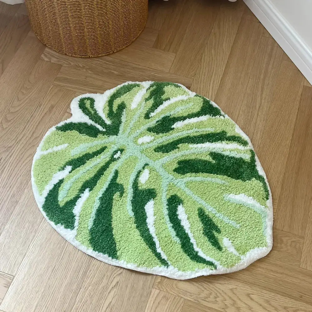 Tapis de bain en forme de feuille verte avec des accents blancs et vert foncé, fabriqué en matériau moelleux.