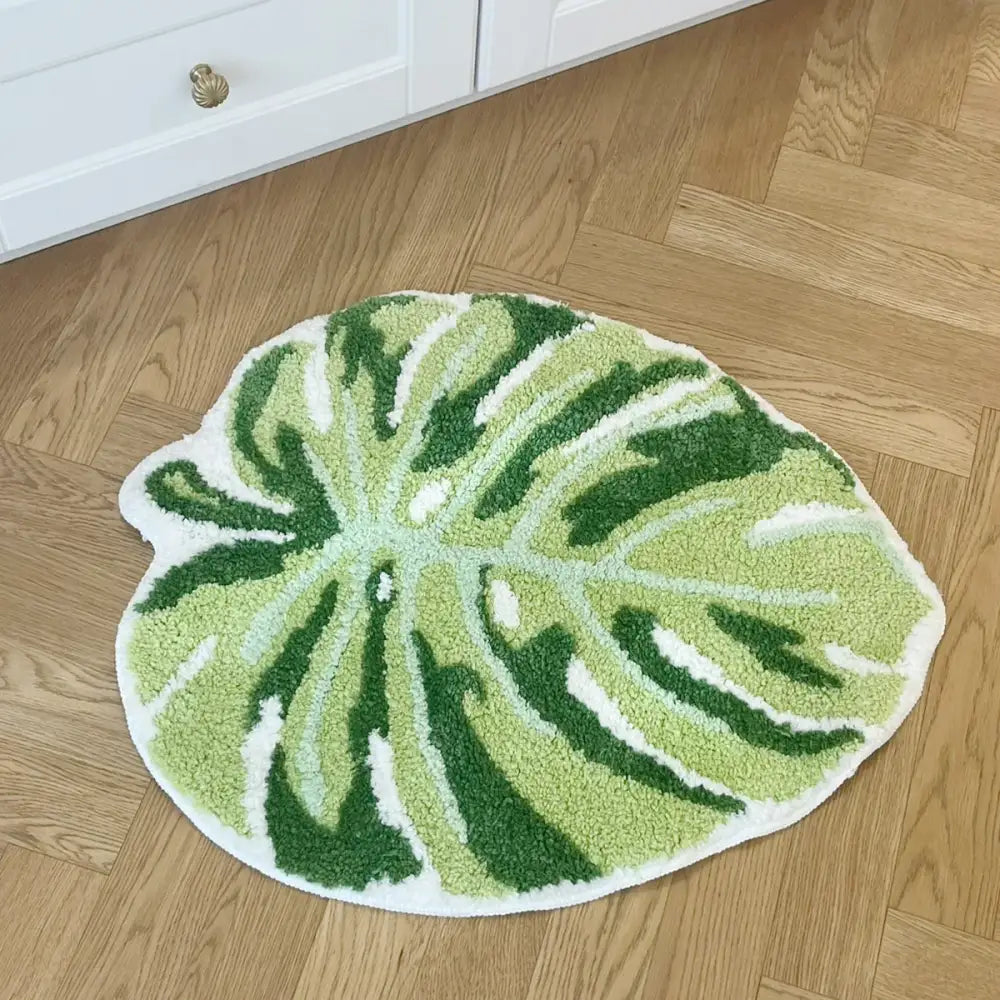 Tapis de bain vert en forme de feuille avec fond blanc, design à poils texturés.