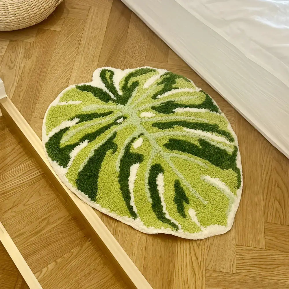 Tapis de bain en forme de feuille verte avec un design texturé et un matériau en fibres naturelles.