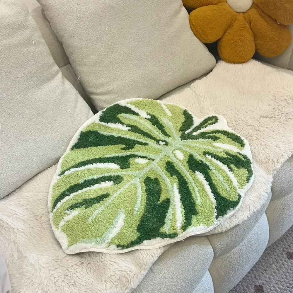 Coussin de lancer en forme de feuille verte avec des accents blancs et vert foncé, fabriqué en matériau moelleux.