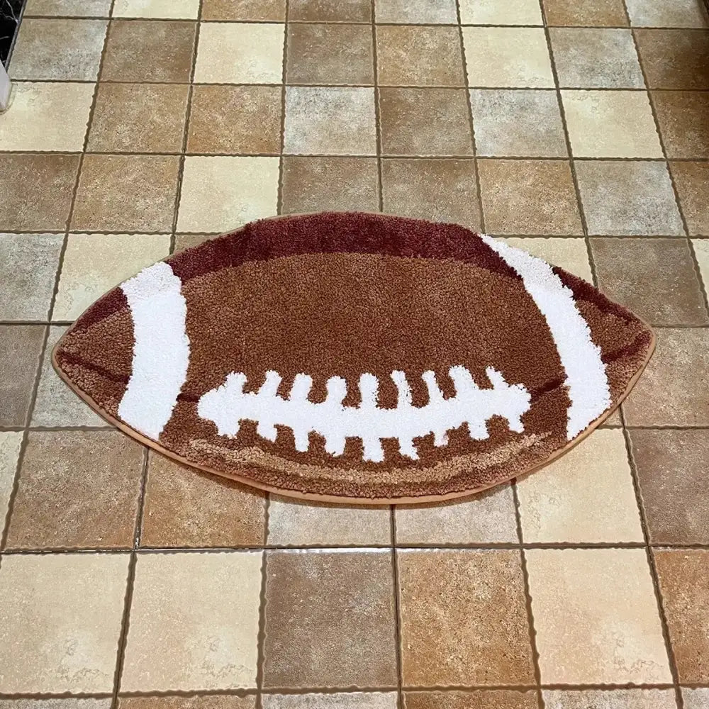 Tapis de bain brun en forme de ballon de football avec lacets blancs et rayures, matériau moelleux.