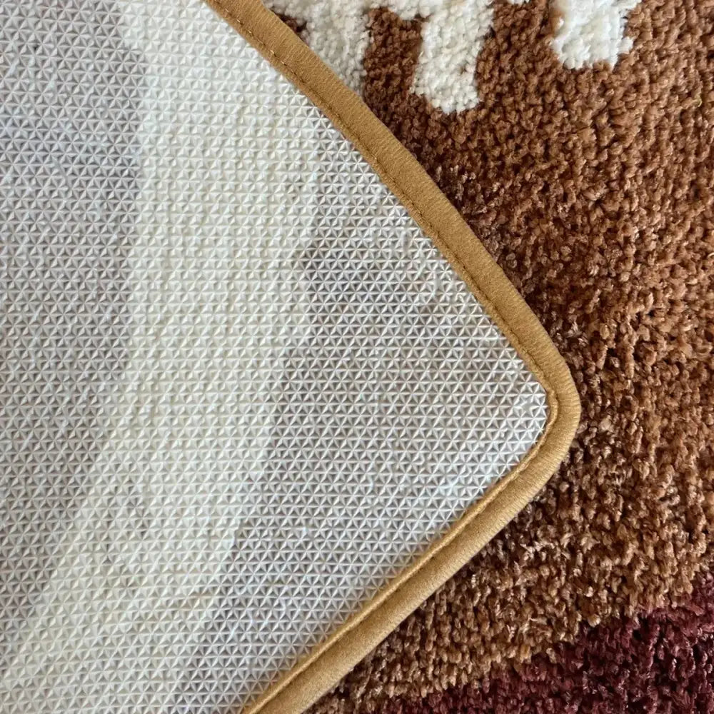 Tapis de bain marron et blanc avec un design texturé, probablement en microfibre.