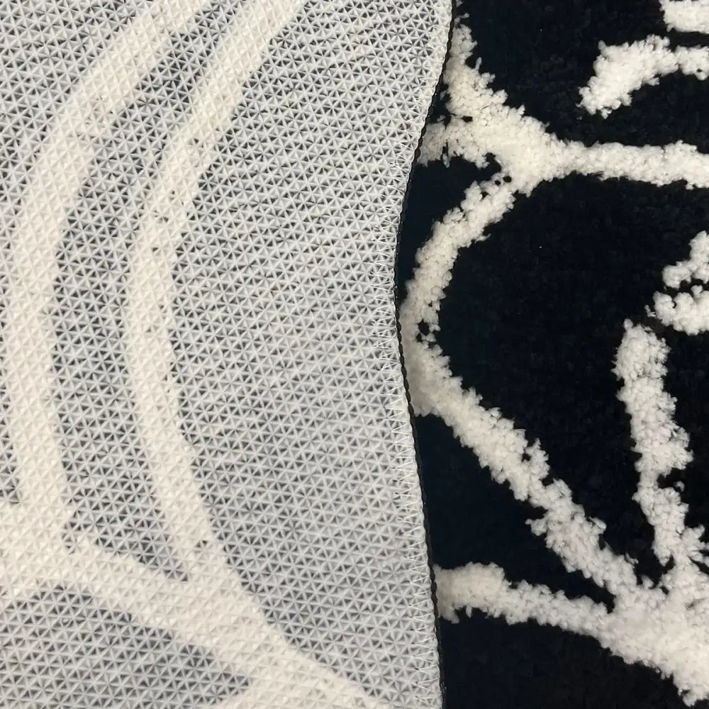 Tapis à motif noir et blanc avec une pile texturée, probablement fabriqué en fibres synthétiques.