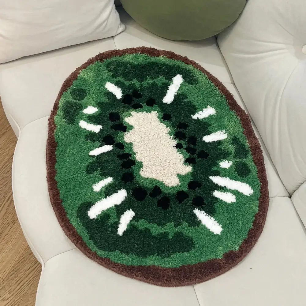 Tapis de bain en forme de kiwi avec des tons verts et bruns, matériau moelleux, détails de graines blanches.