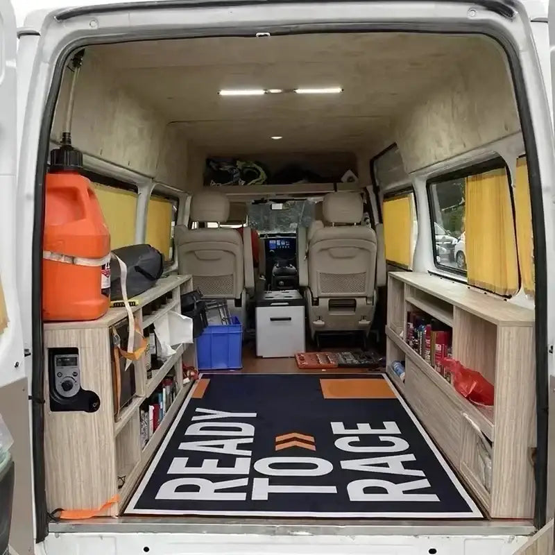 Tapis ktm ready to race noir avec texte blanc et accents orange posé dans l intérieur d un van