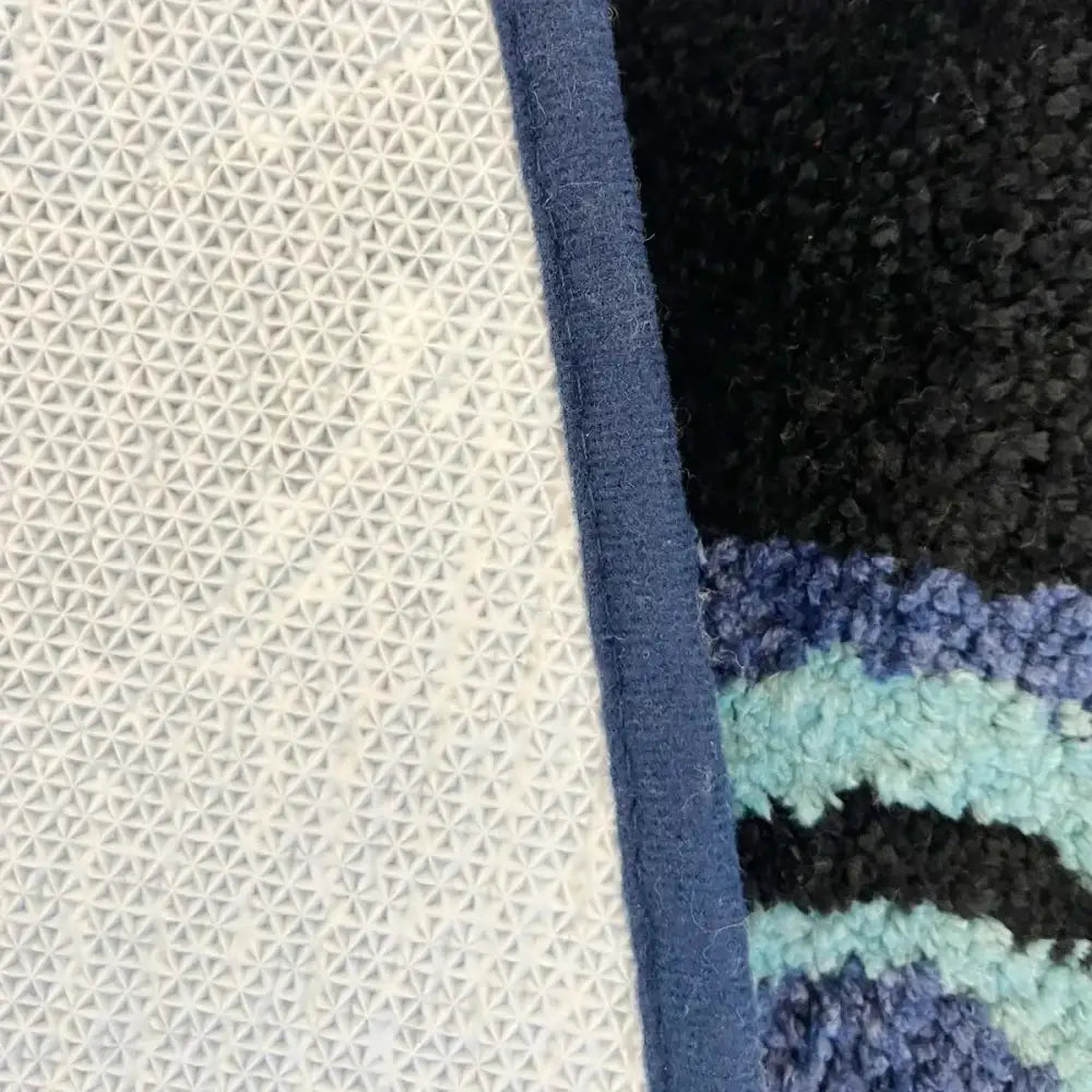 Tapis de bain rayé bleu avec surface texturée et dos moelleux.