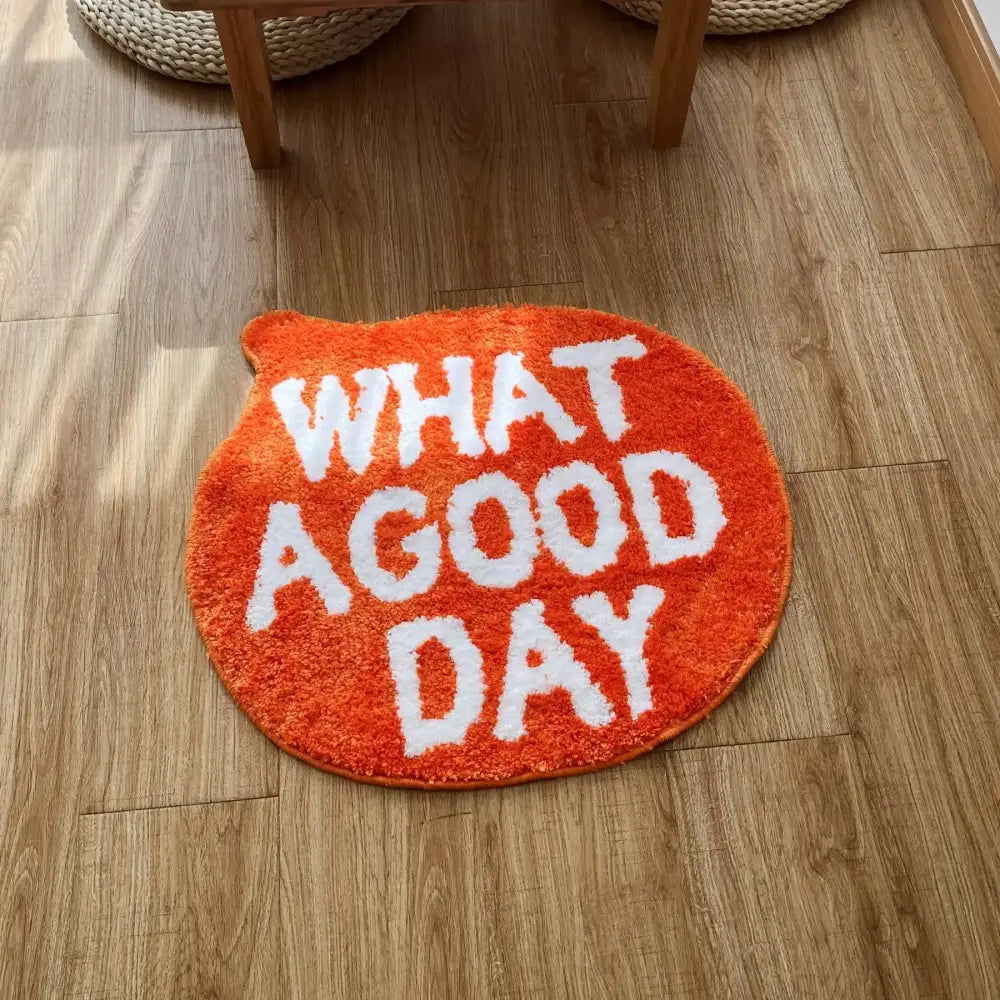 Tapis de bain en peluche orange avec du texte brodé blanc indiquant « quelle belle journée »