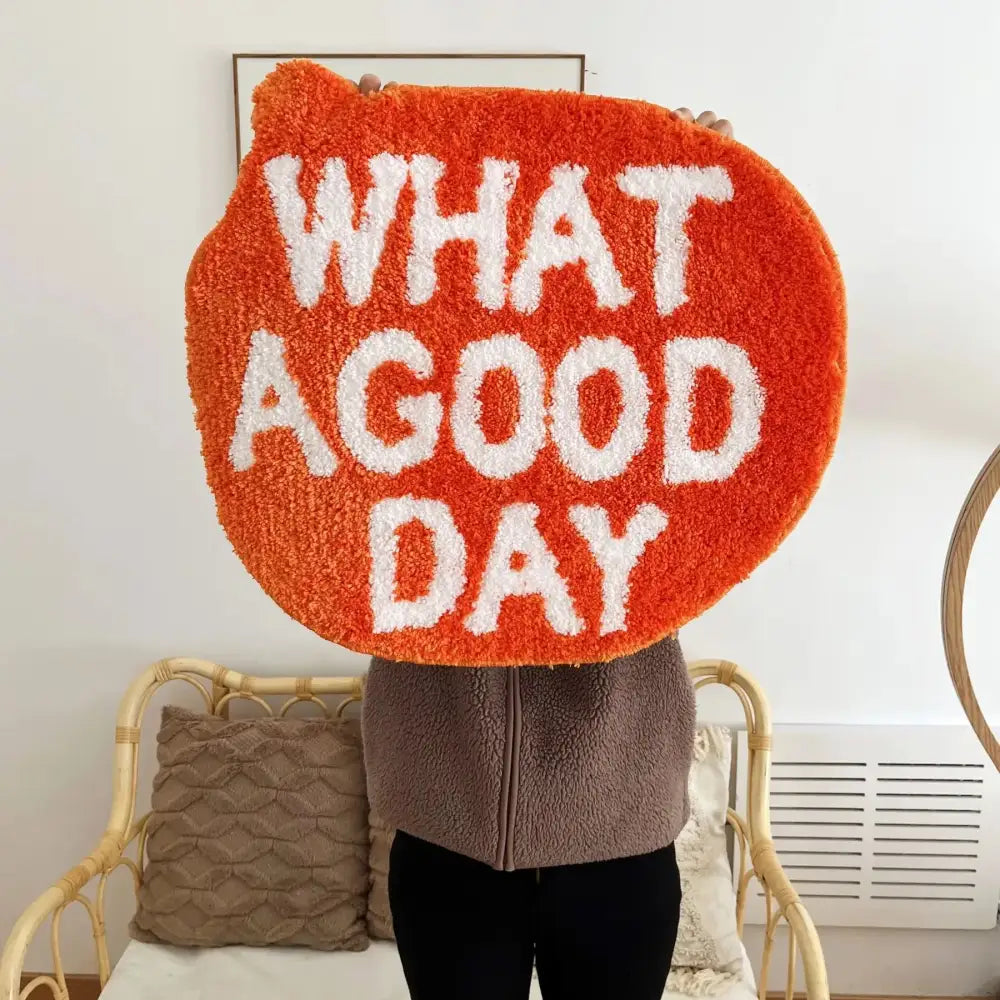 Tapis en peluche orange avec du texte brodé blanc indiquant « quelle belle journée »