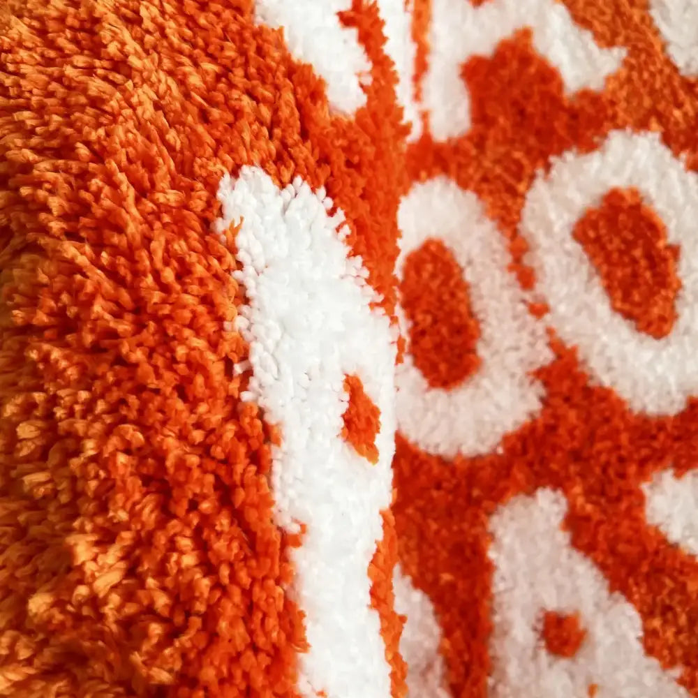 Serviette en peluche orange et blanche avec une texture à boucles.