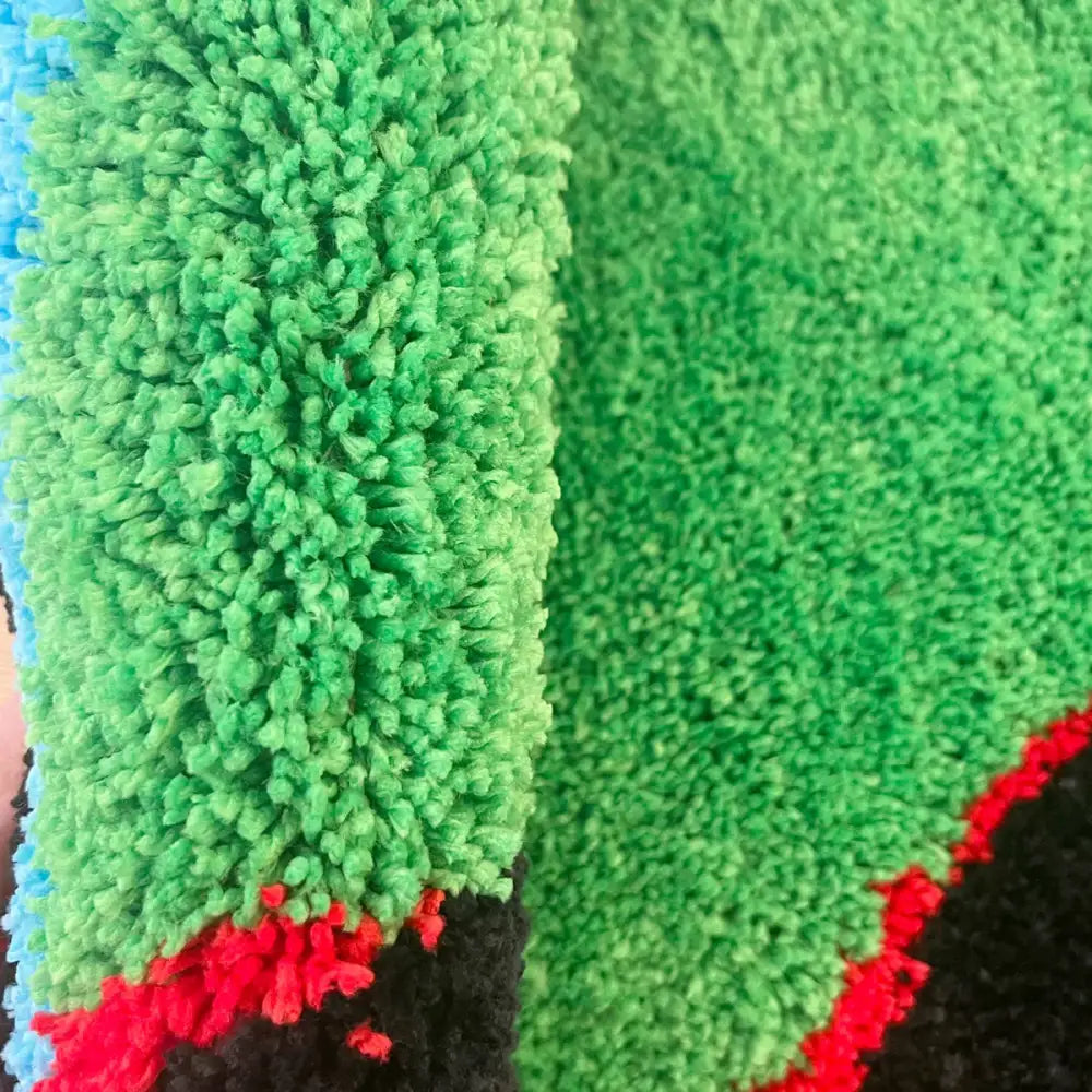 Tissu vert, pelucheux, texturé avec des accents rouges et noirs.