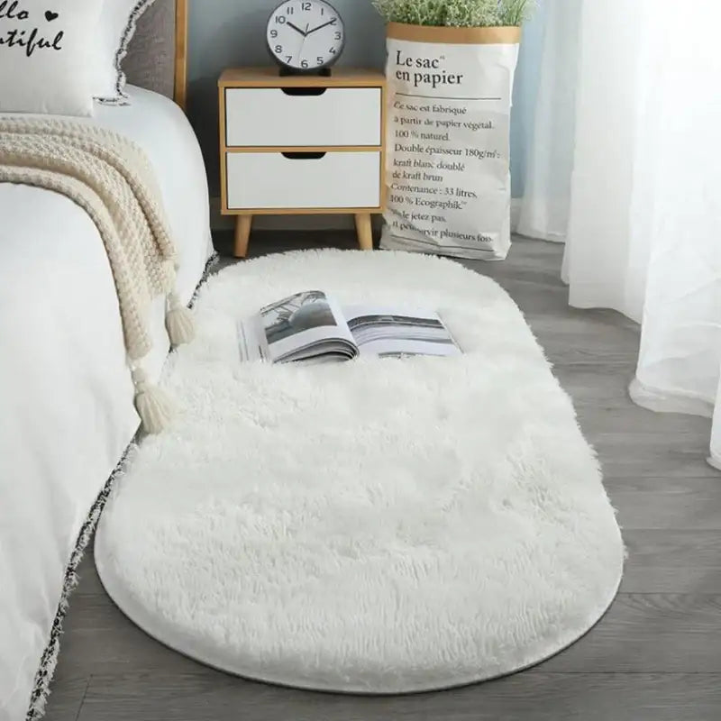 Coussin de sol blanc et moelleux avec un motif texturé et un livre ouvert sur le dessus.