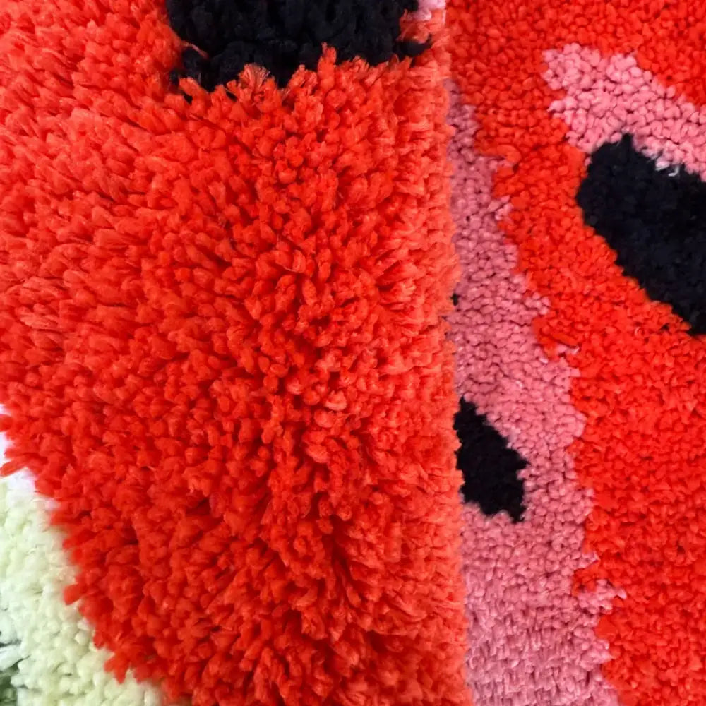 Tapis en peluche rouge et noir avec motif coccinelle, probablement d’une marque populaire de décoration intérieure.