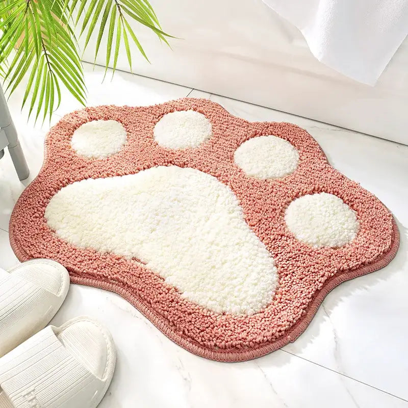Tapis de bain rose et blanc avec empreinte de patte en matériau doux et moelleux.