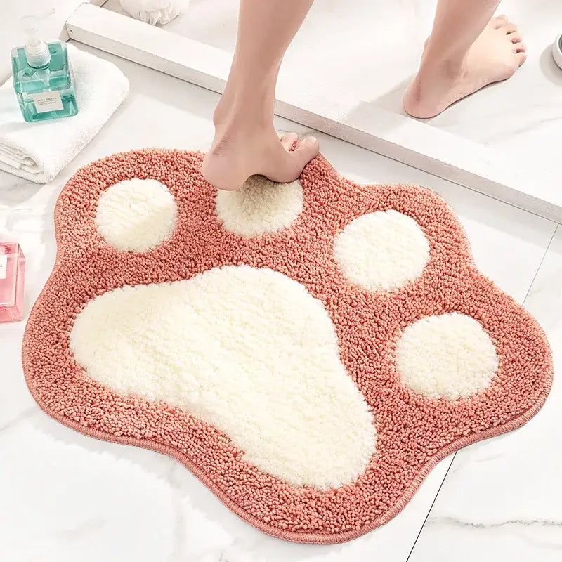 Tapis de bain rose et blanc avec empreinte de patte en matériau doux et moelleux.