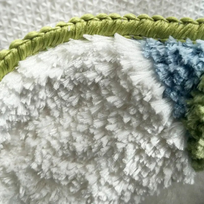 Tapis de bain au crochet vert et bleu avec texture moelleuse blanche.