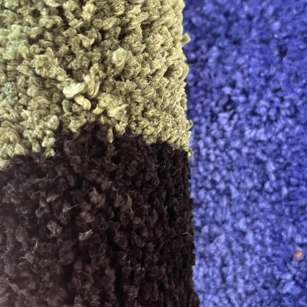 Carrés de tapis en peluche trois tons en olive, bleu marine et violet foncé avec une peluche texturée.