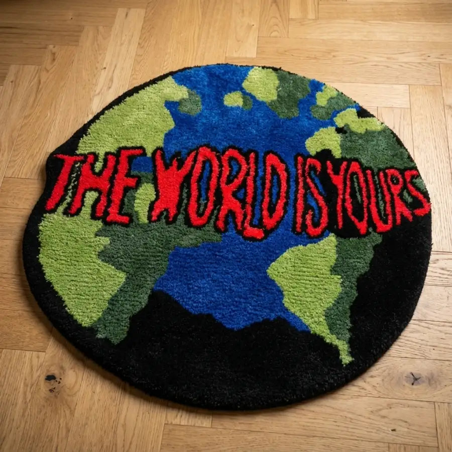 Tapis rond avec design de carte du monde, fond noir, continents verts et bleus, texte rouge ’le monde est à vous’assistant: tapis rond présentant une carte du monde vibrante en nuances de vert pour les masses terrestres et bleu pour les océans sur un fond noir contrastant