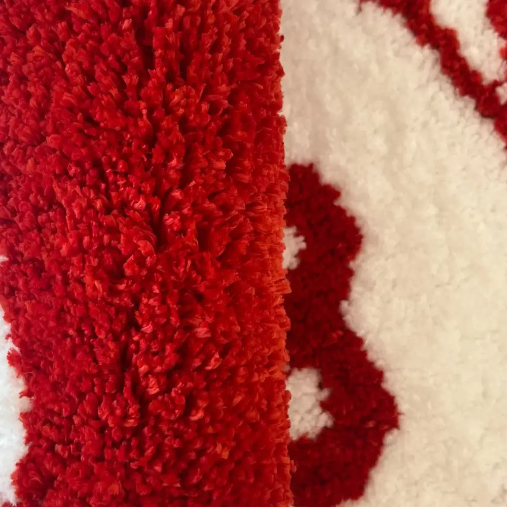Un tapis moelleux rouge et blanc avec une surface texturée et hirsute.