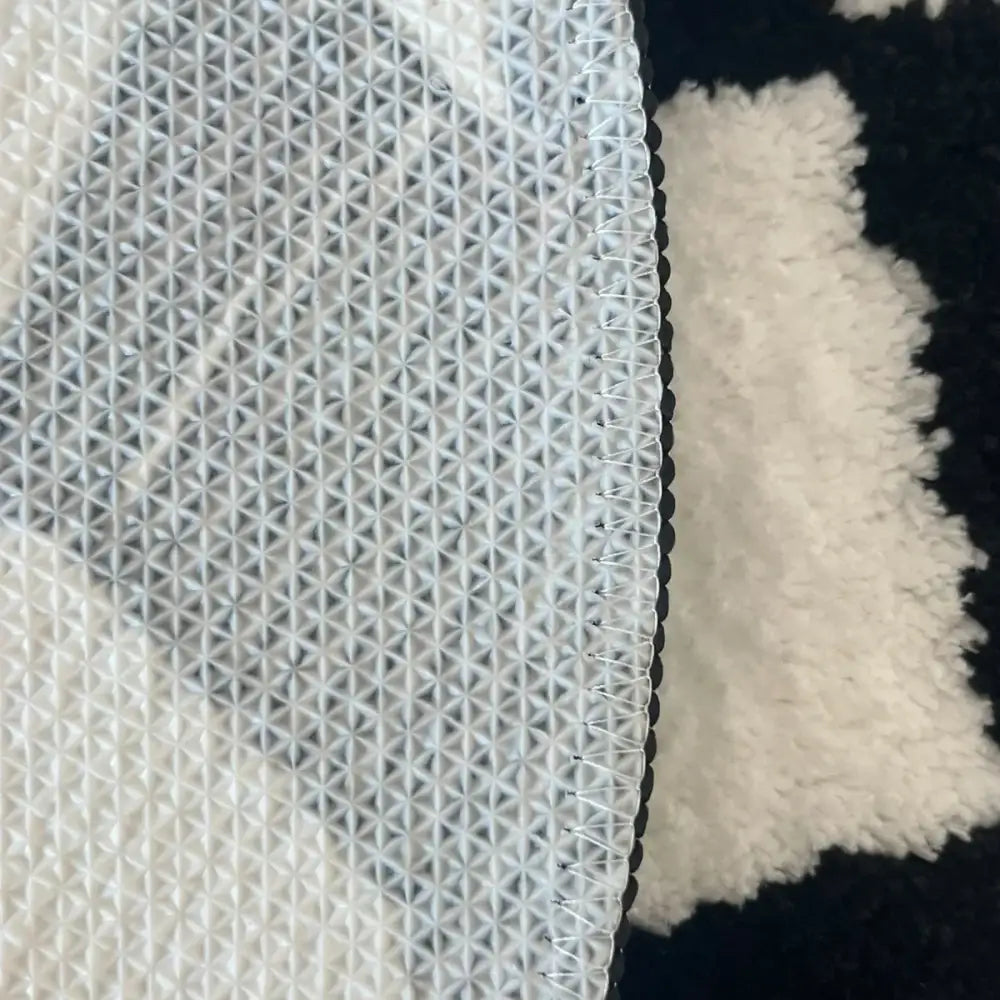 Tissu maillé blanc avec un tissage texturé à motif losange et une couture renforcée le long du bord.