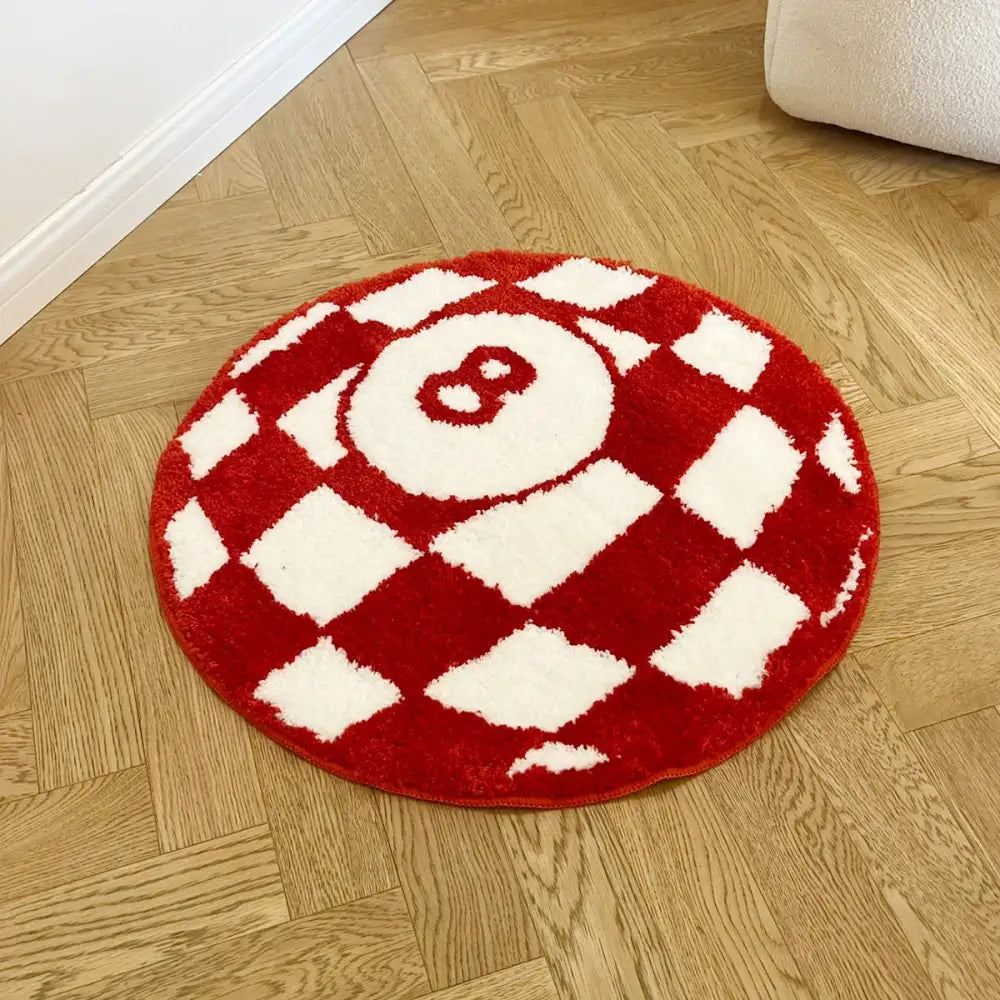 Tapis circulaire en peluche rouge et blanc arborant un motif à carreaux proéminent avec un numéro huit brodé au centre.