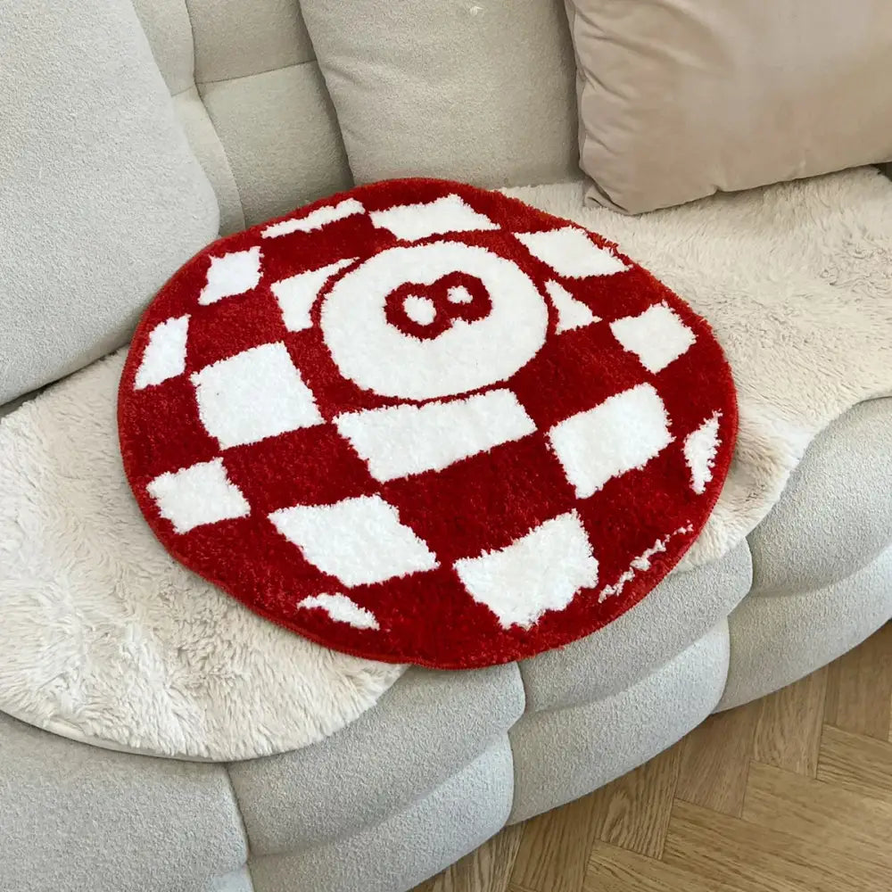 Tapis circulaire à carreaux rouges et blancs avec un design central représentant le chiffre huit, fabriqué en matériau moelleux et duveteux.