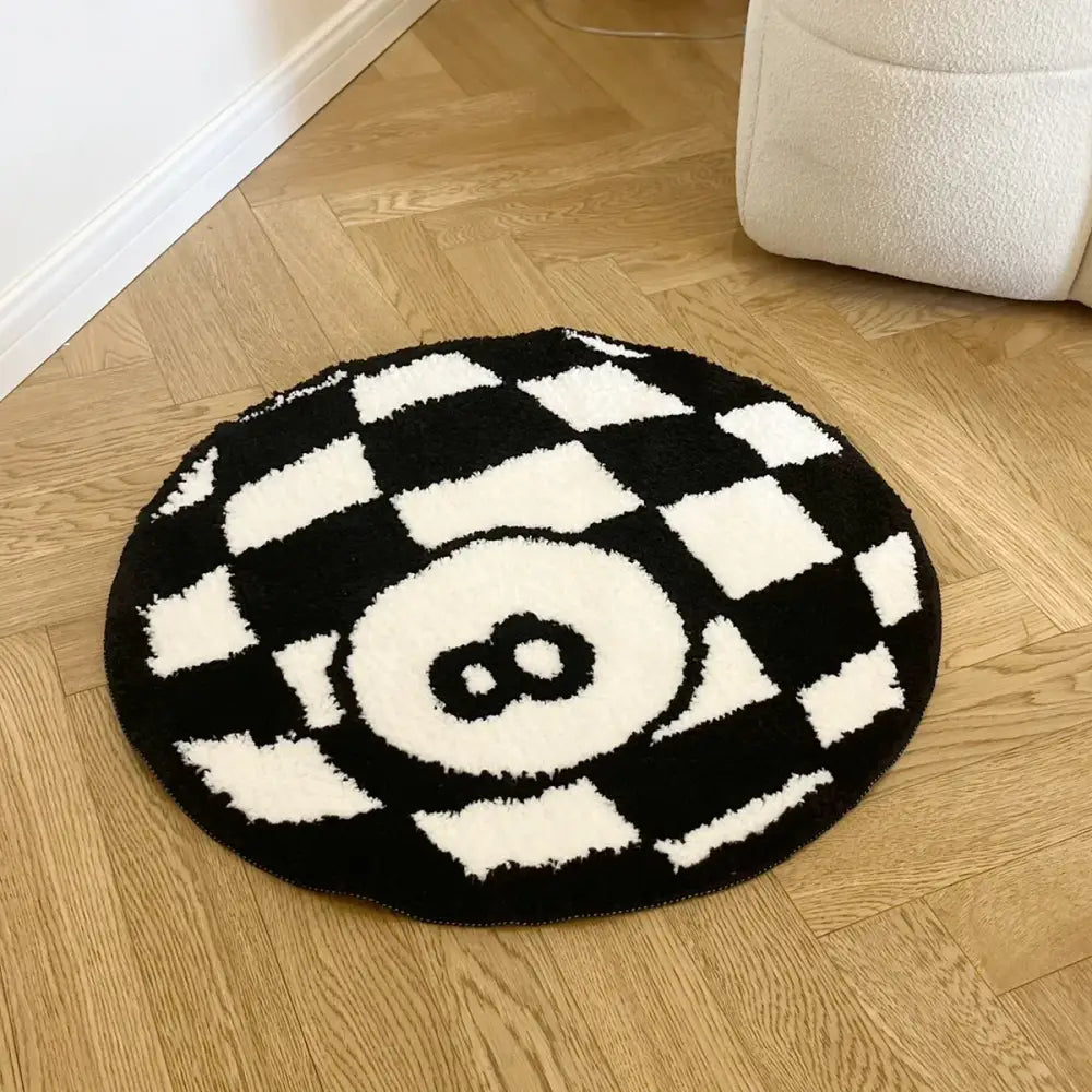 Tapis circulaire à carreaux noir et blanc à texture moelleuse orné d’un chiffre huit brodé au centre.