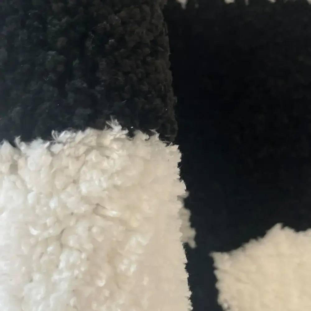 Tissu en polaire duveteuse noir et blanc avec une surface texturée moelleuse.