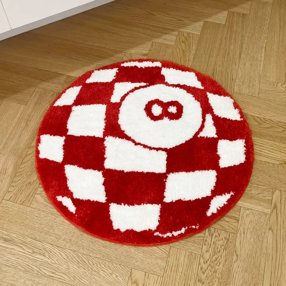 Tapis circulaire à carreaux rouges et blancs doté d’une texture moelleuse et duveteuse avec un design brodé d’un numéro huit au centre.