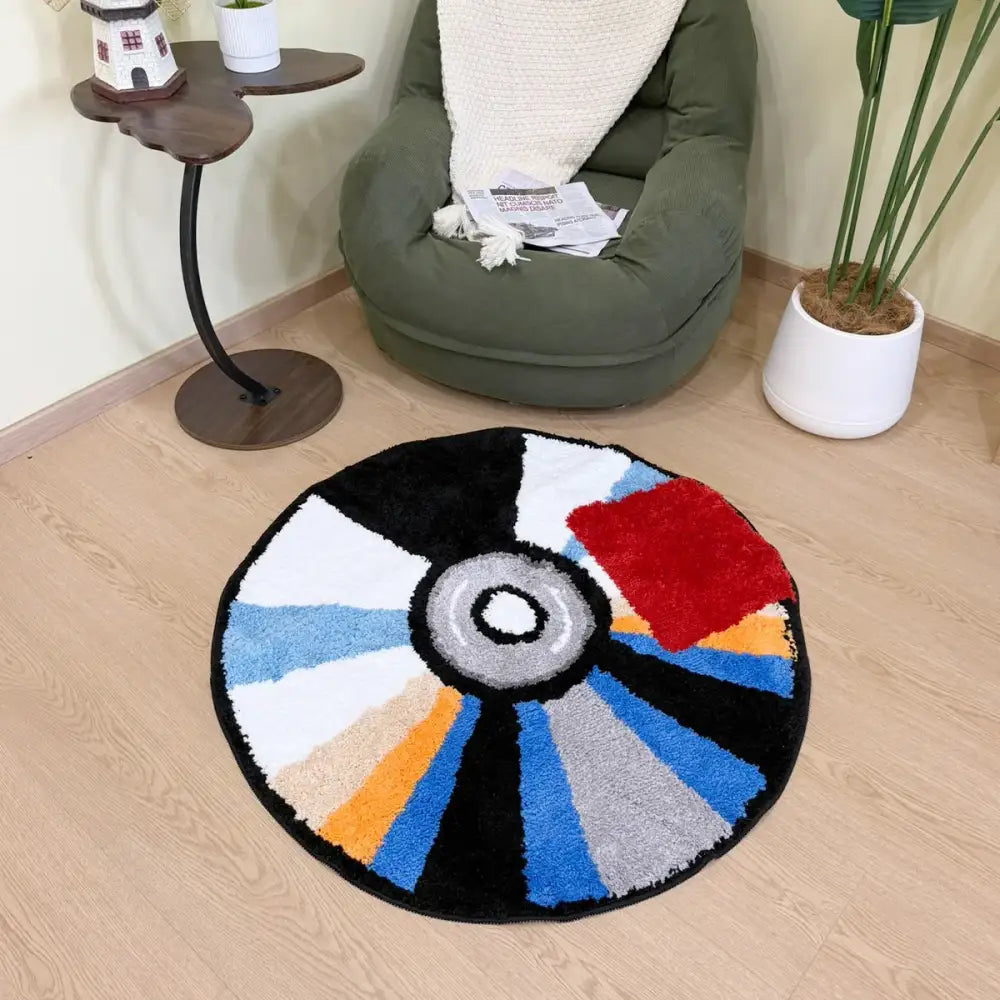 Tapis rond avec un design de roue colorée, fond noir et rayons vibrants en orange jaune bleu rouge vert blanc gris
