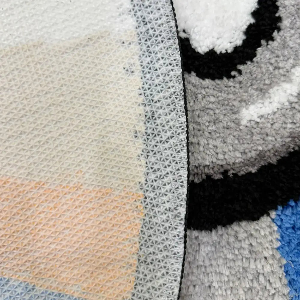 Tapis de bain rayé gris et noir avec dos texturé, probablement en microfibre ou matériau similaire.