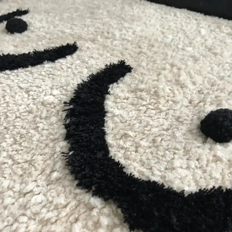 Un tapis moelleux blanc avec un design de visage souriant noir et duveteux.