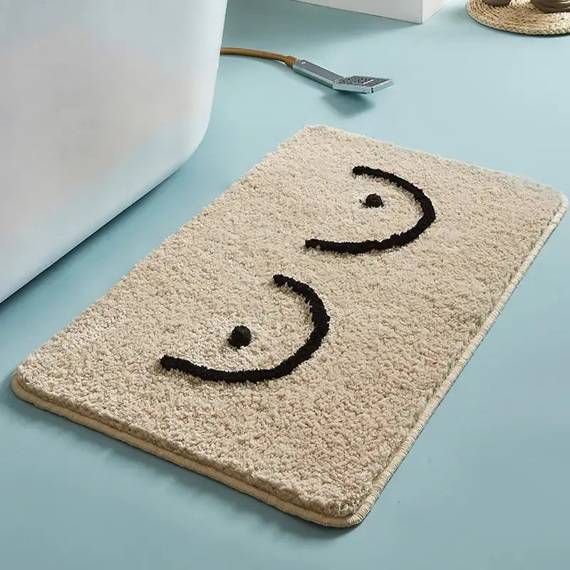 Tapis de bain en peluche beige avec motif de visage souriant brodé en noir.