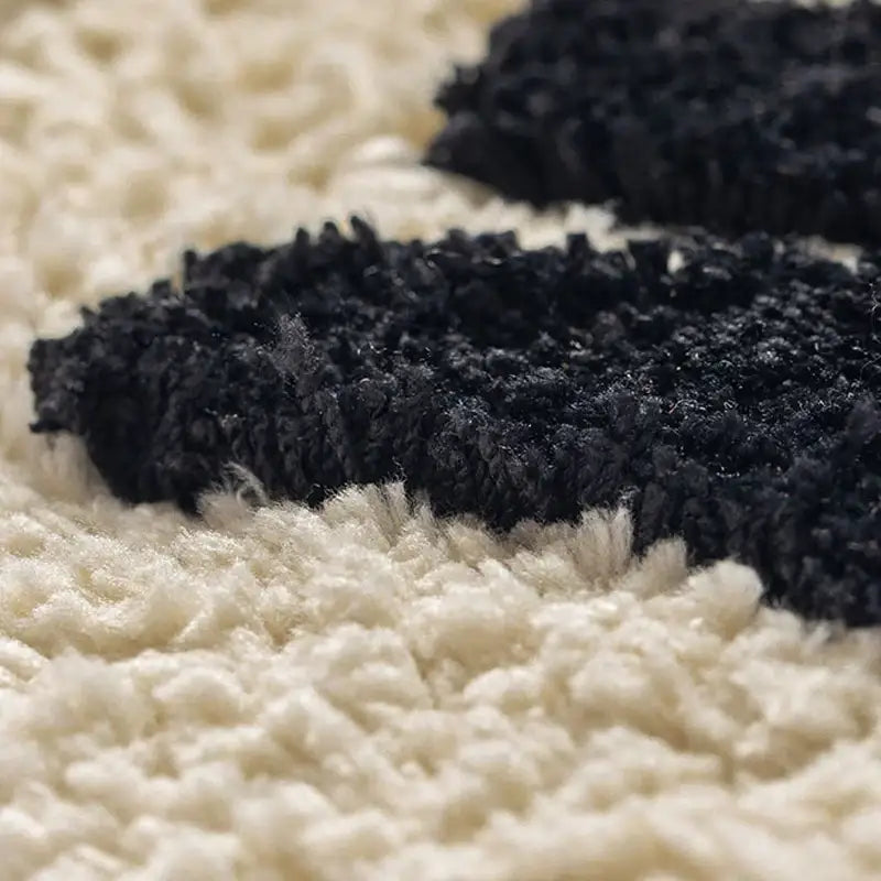 Tapis en peluche noir et crème avec une surface texturée et moelleuse.