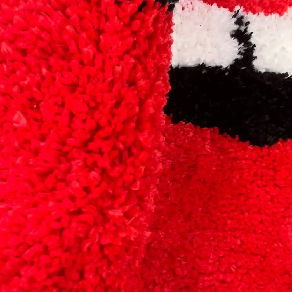 Couverture moelleuse rouge avec des accents noir et blanc, probablement en microfibre ou en tissu pelucheux.