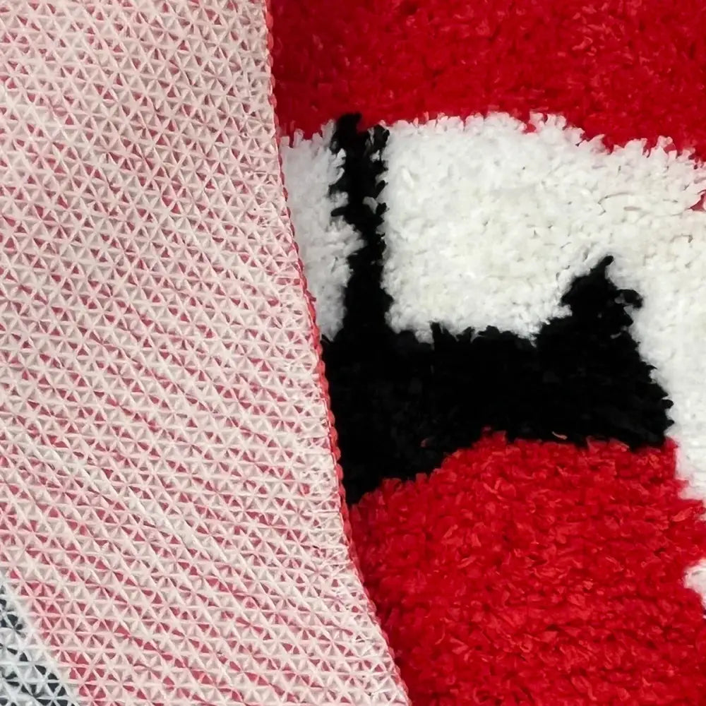 Couverture texturée rouge et blanche avec motif de chat noir, matériau doux.